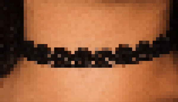 Vídeo pixelado mostrando um detalhe de colar preto num pescoço. Logo abaixo o vídeo com acessibilidade em Libras. Fundo branco, mulher branca, blusa preta, cabelo amarrado, sinalizando.
